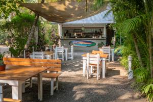 restauracja z drewnianymi stołami i krzesłami oraz basenem w obiekcie Living Hotel w mieście Nosara