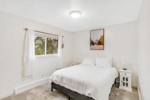 a white bedroom with a bed and a window at Bear Necessities in Eagle River