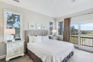 a white bedroom with a large bed and windows at Sanderling Resort Residences in Duck