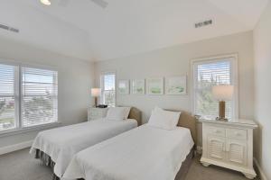 two beds in a white room with windows at Sanderling Resort Residences in Duck