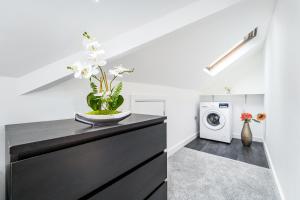 a laundry room with a black dresser and a washing machine at Twickenham Apartments by Charles in Teddington