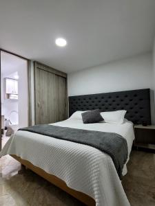 - une chambre avec un grand lit et une tête de lit noire dans l'établissement Modern High-Rise 2/2 Apartment with City View., à Sabaneta