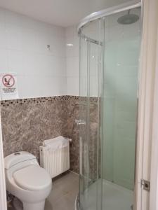 a bathroom with a toilet and a glass shower at Hostal JC in Puerto Natales