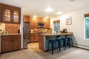 una cocina con armarios de madera y taburetes de barra azul en Adventure awaits in cozy retreat between Vail and Beaver Creek en Vail