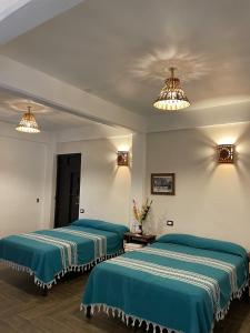 duas camas num quarto com lençóis verdes e luzes em Hotel Yubazuu em San Pablo Villa de Mitla