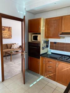 une cuisine avec des placards en bois et un salon dans l'établissement apartement Lac 2, à El Aouina