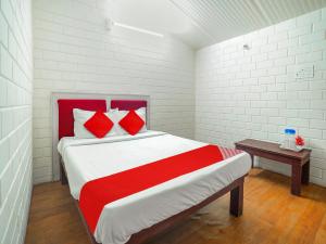 a bedroom with a large bed with red and white pillows at Manyura Hotels & Resorts in Vaiasavettikādu
