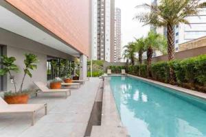 - une piscine avec des bancs et des palmiers dans un bâtiment dans l'établissement Vitrali Deluxe Moema ao lado do metrô, à São Paulo