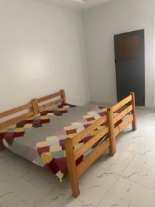 ein Holzbett mit einer bunten Bettdecke in einem Zimmer in der Unterkunft Mondialaw in Toubab Dialao