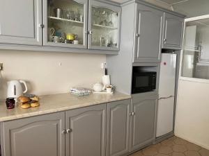 uma cozinha com armários cinzentos e um frigorífico branco em Canice Mooney Self Catering Holiday Home em Drumshanbo