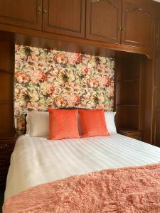 uma cama com duas almofadas laranja e uma cabeceira floral em Canice Mooney Self Catering Holiday Home em Drumshanbo