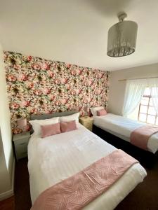 two beds in a room with floral wallpaper at Canice Mooney Self Catering Holiday Home in Drumshanbo