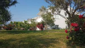 ein weißes Haus mit roten Blumen im Hof in der Unterkunft Apartment Ljubac 1 in Krneša