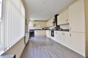 a kitchen with white cabinets and a wooden floor at StayRight 3-Bed Home Near Central Cardiff- Sleeps 8, Twin Or King Beds in Cardiff