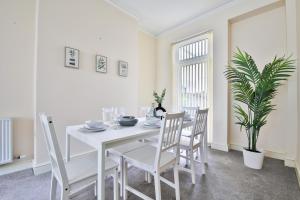 a white dining room with a white table and chairs at StayRight 3-Bed Home Near Central Cardiff- Sleeps 8, Twin Or King Beds in Cardiff