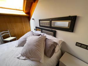 a bedroom with a bed with white pillows and a mirror at Duplex en Casco Histórico in León