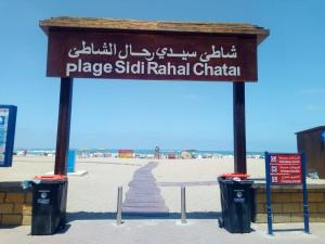 un cartel en la playa con dos cubos de basura en Sidi rahal chat, en Sidi Rahal