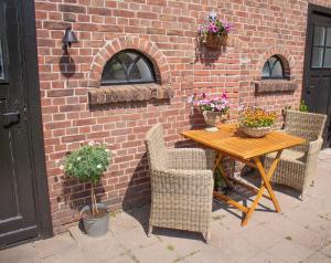 une table en bois avec des chaises et des fleurs sur un mur de briques dans l'établissement B&B de Olde Hilde, à Eibergen