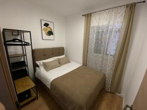 ein kleines Schlafzimmer mit einem Bett und einem Fenster in der Unterkunft Apartman "Borićevac" in Sinj