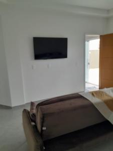 - une chambre avec un lit et une télévision murale dans l'établissement Sobrado Itajuba, à Barra Velha