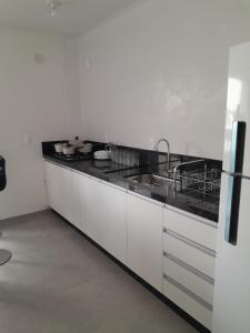 - une cuisine blanche avec évier et comptoir dans l'établissement Sobrado Itajuba, à Barra Velha