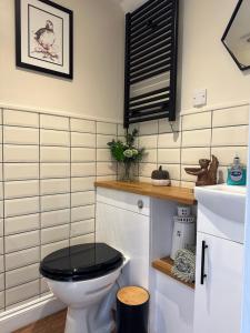 a bathroom with a black toilet with a black seat at White Mermaid Cottage Anglesey Holidays in Newborough