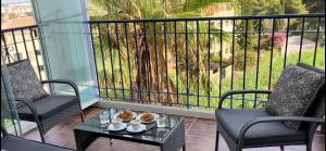 Un balcón con 2 sillas, una mesa y un árbol en Apartment Summer Vibes Miraflores - La Cala de Mijas, en La Cala de Mijas