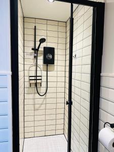 a shower with a black and white tiled wall at White Mermaid Cottage Anglesey Holidays in Newborough