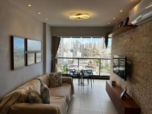 a living room with a couch and a view of a city at Salvador farol da barra 01 Apartamento Vista Mar in Salvador