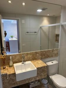 a bathroom with a sink and a toilet and a mirror at Salvador farol da barra 01 Apartamento Vista Mar in Salvador