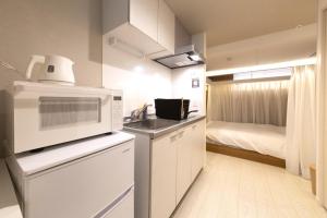 eine kleine Küche mit einer Mikrowelle und einem Bett in der Unterkunft Maruka Osaki Room C - Vacation STAY 53141v in Tokio