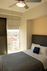 a bedroom with a large bed with a large window at Puerta Alameda Suites México in Mexico City