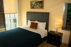 een slaapkamer met een groot bed en een lamp bij Puerta Alameda Suites México in Mexico-Stad