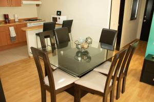 a glass dining room table with chairs and a kitchen at Puerta Alameda Suites México in Mexico City