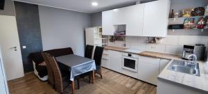 uma cozinha com armários brancos, uma pequena mesa e um lavatório em Private Apartment em Langenhagen
