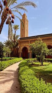a building with a clock tower in a park at Riad lalla aicha in Marrakech