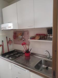 una cucina con lavello, piano cottura e armadietti bianchi di Residence San Nicola 3 a San Massimo