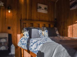 a bedroom with a bed with a wooden wall at Wampford Woodland Retreat - Kings Cabin in George Nympton