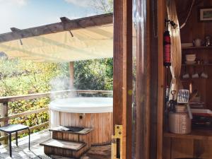 a hot tub on the deck of a house at Wampford Woodland Retreat - Kings Cabin in George Nympton