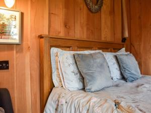 a bed with blue pillows in a room with wooden walls at Wampford Woodland Retreat - George Cabin in George Nympton