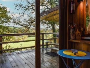 a room with a view of a deck with a table at Wampford Woodland Retreat - George Cabin in George Nympton