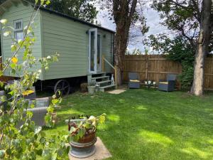 a green house in a yard with a fence at Beautiful shepherd’s hut in Newmarket