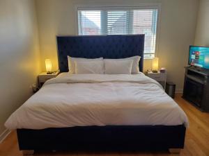 a bedroom with a large bed with a blue headboard and a television at RAESABU GUEST HOUSE in Brampton