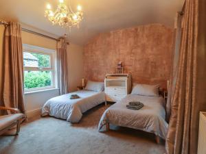 a bedroom with two beds and a window and a chandelier at 20 Wool Road in Oldham