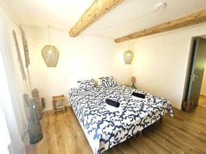 Schlafzimmer mit einem Bett mit einer schwarzen und weißen Bettdecke in der Unterkunft Le gîte de la marquise - Elégant appartement avec terrasse - in Montboucher-sur-Jabron