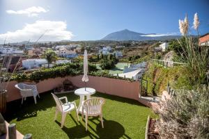 a patio with two chairs and a table on the grass at Espacio Antares in Icod de los Vinos