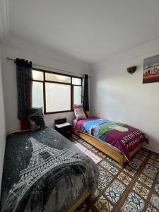 a bedroom with two beds and a window at Maison Berj in Oualidia