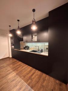 a large kitchen with black cabinets and a sink at BoleslaviaApartments - Apartament Arte 2 - parking free, EV in Bolesławiec