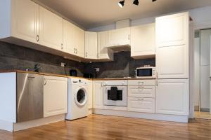a kitchen with white cabinets and a washer and dryer at Spacious 2 Bedroom Apartment in Hackney in London