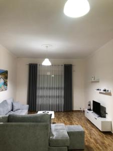 a living room with a couch and a tv at Drini Apartments in Përmet